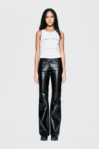 Model wearing a white tank top and black leather pants on a white background
