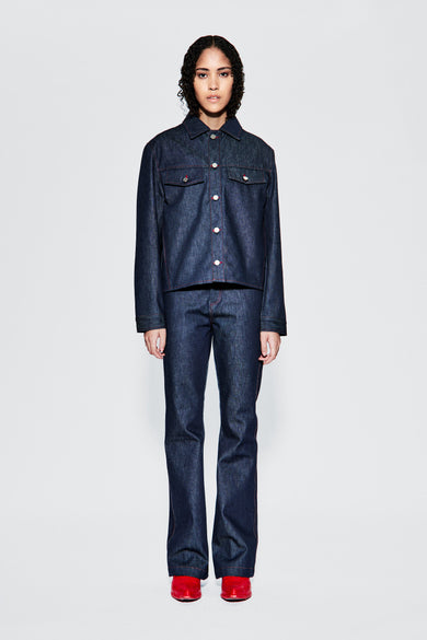 Raw denim trucker jacket worn from front on female model, showing chest pockets and fit.