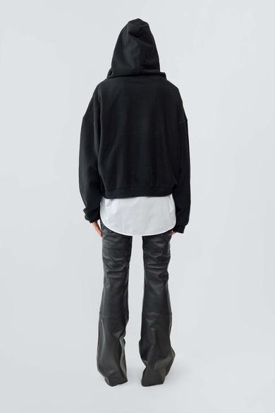 Back view of model wearing the Y2K-inspired Leather Kick Pants feature a low waist, slim fit, and retro kick-flare silhouette. Made from upcycled leather, these minimalist pants have a pocket-free design and a hidden side zipper for a sleek, streamlined look. Runs large—consider sizing down.