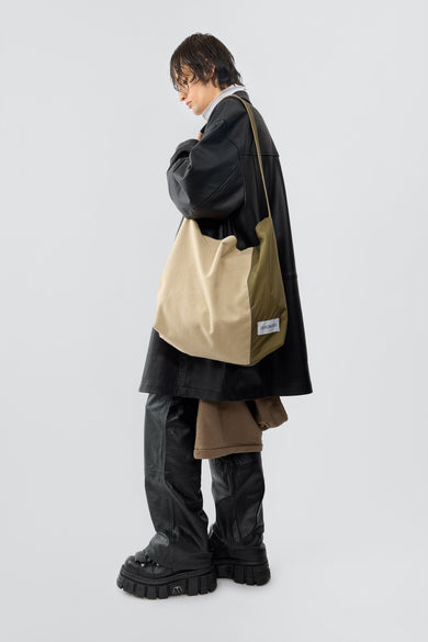 Model wearing sling bag in beige and olive, made out of cotton and polyamide off-cuts from deadwoods main production.