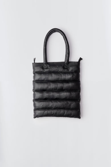 Front view of Tundra Tote, a unisex puffer tote bag with a sturdy shoulder strap, zip closure, and practical inside zip pocket. Made from upcycled leather, with a lining and filling from recycled plastic bottles.