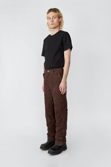 Model wearing brown Deadwood straight cut cargo pants with slightly dropped crotch, zip fly and workwear-inspired double waist pockets and leg pockets. One 32” length fits all. Made from recycled suede. 