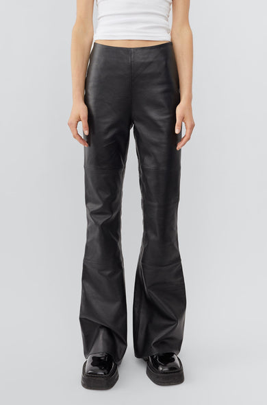 Model in black leather Kick Pants by Deadwood, slim-fit Y2K kick-flare with sustainable recycled materials.