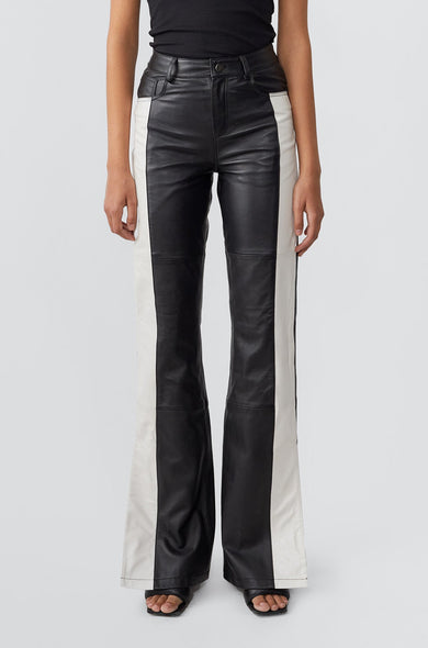 Model in Prance Black and White Leather Pants by Deadwood, featuring white stripes, bootcut fit, and slits at the leg opening, made from soft upcycled lambskin.