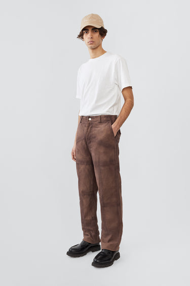 Model in Phil Suede Pants in brown by Deadwood, featuring a brushed patchwork design, made from upcycled goat suede and lined with recycled PET fabric.
