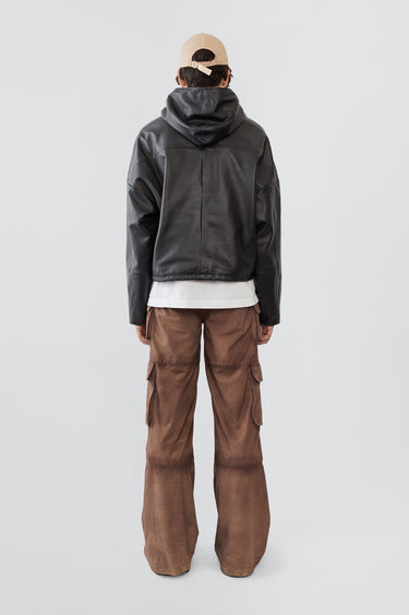 
A male model wearing the Deadwood Cargo Leather Pants. These workwear-inspired leather pants feature a wide, relaxed fit with a flowing silhouette. Designed with double waist pockets, multiple cargo pockets with hidden push-button closures, and a mid-waist zip fly. Crafted from upcycled leather and lined with fabric made from 100% recycled plastic bottles.