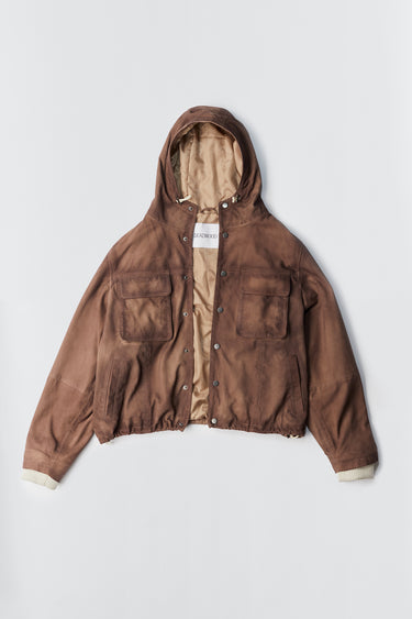 Picture of Kodiak in brown, a hip-length leather parka made from recycled suede. The jacket features duo chest pockets, a cozy hood, side pockets, and an inside pocket. A drawstring at the hood and bottom hem allows for an adjustable fit. The outer shell is crafted from upcycled deadstock suede leather, while the lining is made from recycled PET bottles for a sustainable touch.