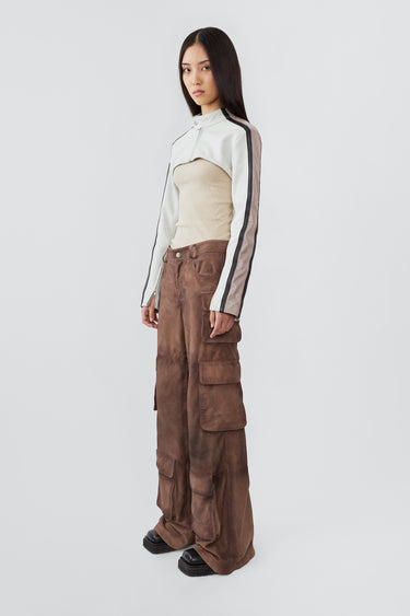 Side profile of model in Sephir ultra-cropped leather jacket in white with black stripes on the sleeves. Rracer-inspired with upcycled materials and bold design