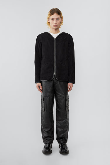 Front view of model wearing liner jacket in black suede. The jacket features upcycled suede and a front zipper closure.