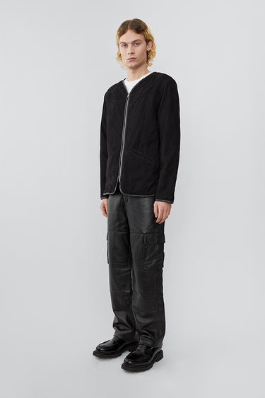 side view of model wearing liner jacket in black suede. The jacket features upcycled suede and a front zipper closure.