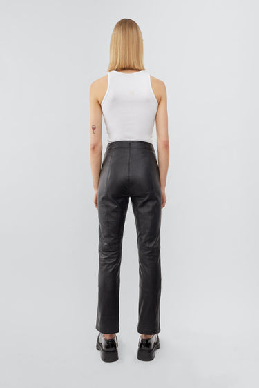 backview of a model wearing high-waisted pants with a slim leg and ankle-length crop. The pants feature a split hem at the front and concealed side zip closure. Made from recycled leather with a lining made from recycled PET bottles.