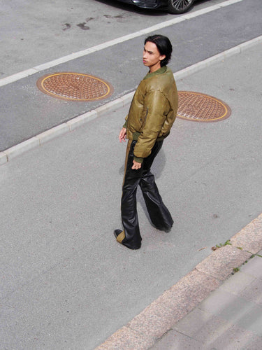 Side view of Men’s Bofinger olive green leather bomber jacket by Deadwood, showcasing sleeve pocket with exaggerated zipper pull.
