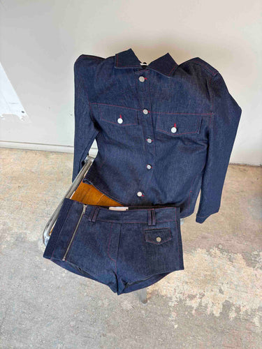 Denim jacket and shorts on a chair standing on a concrete floor with a white wall background