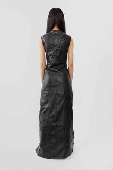 
A female model wears the Ortem Maxi Dress in black, crafted from deadstock leather with a diagonal eyelet slit and adjustable leather laces, lined with recycled PET bottles.