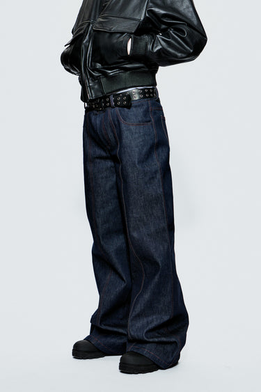 Model wearing a black leather jacket and blue jeans on a light gray background