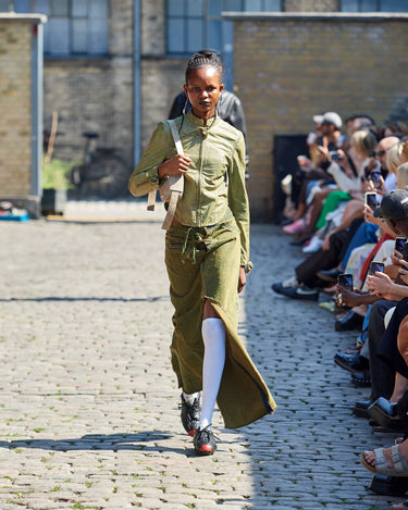 Female model on runway wearing olive outfit from Deadwood Spring/Summer 2025 Collection during Copenhagen Fashion Week. The look features upcycled leather and recycled cotton, reflecting the brand’s commitment to sustainable fashion