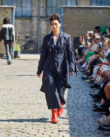 Female model on runway wearing a navy coat from Deadwood Spring/Summer 2025 Collection during Copenhagen Fashion Week. The look features upcycled leather and recycled cotton, reflecting the brand’s commitment to sustainable fashion