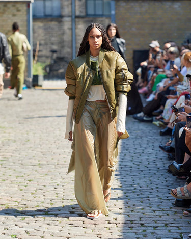 Female model on runway wearing olive and white outfit from Deadwood Spring/Summer 2025 Collection during Copenhagen Fashion Week. The look features upcycled leather and recycled cotton, reflecting the brand’s commitment to sustainable fashion