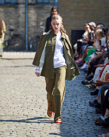 Female model on runway wearing white and olive outfit from Deadwood Spring/Summer 2025 Collection during Copenhagen Fashion Week. The look features upcycled leather and recycled cotton, reflecting the brand’s commitment to sustainable fashion
