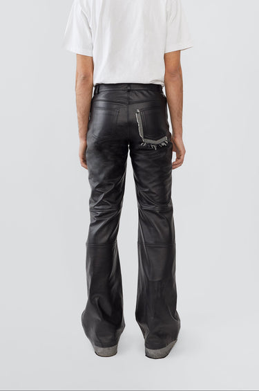 Person wearing black leather pants and a white shirt on a light gray background