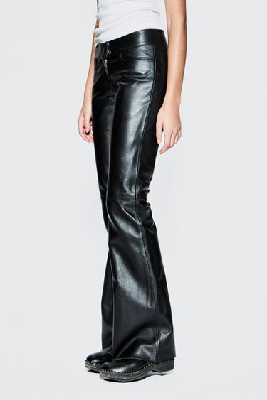 Black leather flared pants worn by a person on a white background