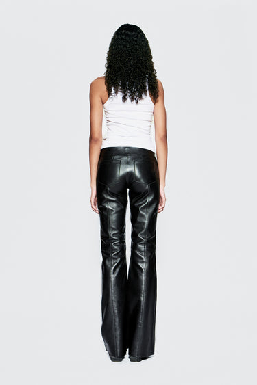 Person wearing black leather pants and a white top on a white background