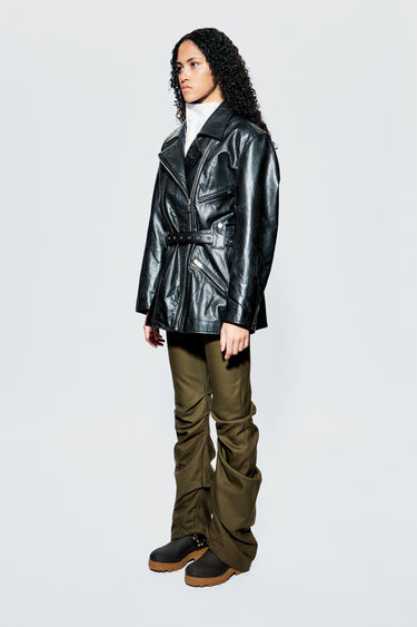 Side profile of Deadwood’s Ann Jacket on model, highlighting extended length and structured leather shape with waist detailing.