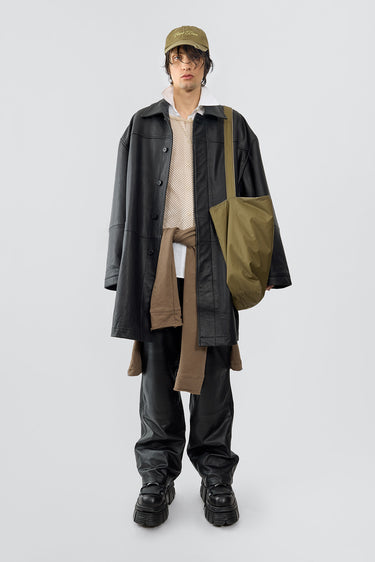 A model is wearing the bloke coat from Deadwood. The Men's Bloke Coat is an oversized coat made from sturdy upcycled grain cow leather. It features a button closure, generous side pockets, and an inside pocket for added functionality. The lining is crafted from 100% recycled plastic bottles, emphasizing sustainability.