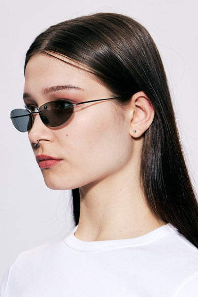 Side profile of female model wearing Colletti sunglasses showing ultra-light matte black recycled steel arms and smoked gunmetal lenses.