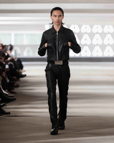 Model wearing a black leather jacket and pantson Deadwood pre-spring 2026 runway show with a blurred background