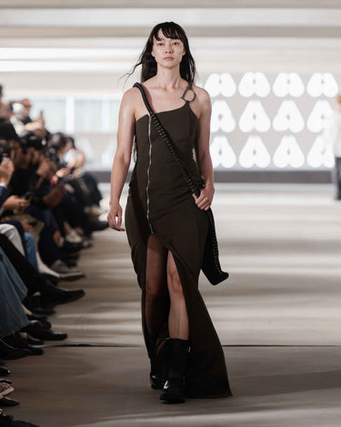 Model walking on on Deadwood pre-spring 2026 runway show wearing a dark green dress with a high slit.