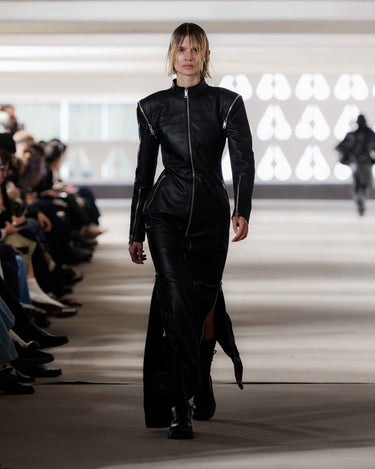 Model wearing a black leather outfit on Deadwood pre-spring 2026 runway show with an audience.