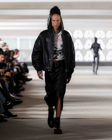 Model walking on Deadwood pre-spring 2026 runway show wearing a black leather jacket, vintage t-shirt and black leather skirt.