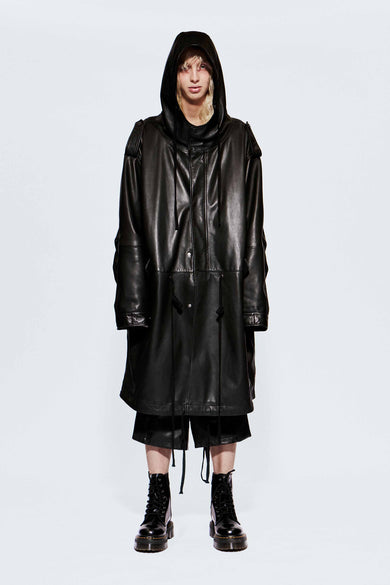 Male model wearing an oversized black recycled leather coat on a white background