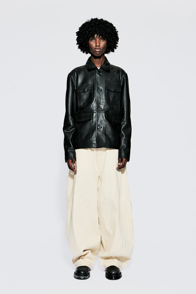 Front view of model wearing a black leather jacket and beige pants on a white background