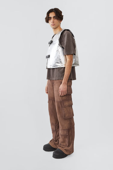 Picture of the side of an model wearing kapok vest, an silver vest with silver colored details and black buckles on the front. Made out of upcycled suede