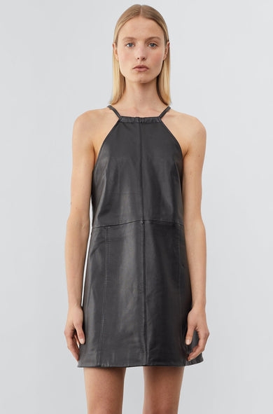 Front view of a model wearing The Kimi Dress, a short, chic cocktail dress made from black upcycled leather. The dress features a slightly A-line shape for a flattering silhouette, with a back slit for added movement and style.