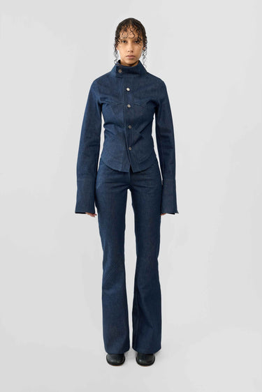 Front view of model wearing a blue raw denim outfit on a white background