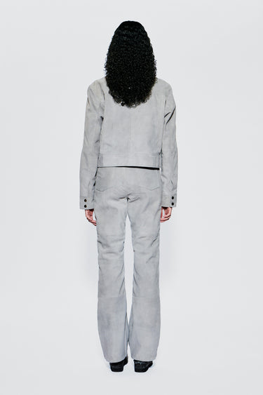 Back view of a model wearing a light gray suede outfit on a white background