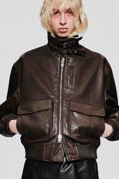 Person wearing a brown leather flight jacket on a plain background