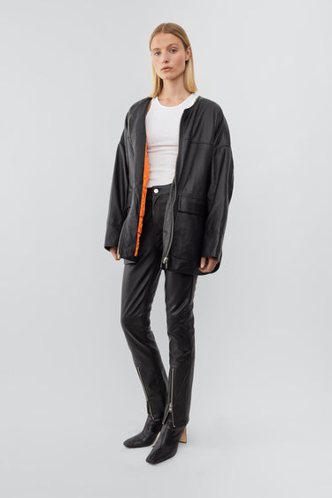 Model wearing black oversized army-liner-inspired Deadwood jacket, made från upcycled lambskin leather. Dropped shoulders, a wide bottom hem, zip closure at center front, and duo waist flap pockets.