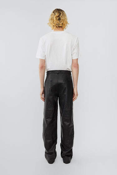 Model wearing wide straight cut Deadwood leather pants with high waist, zip fly and workwear inspired front pocket detail. Flattering jean style back pockets. Made from recycled leather.