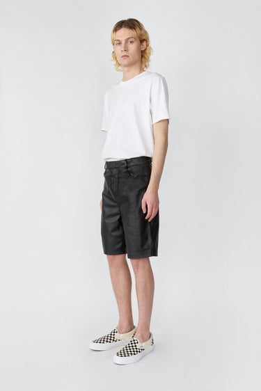 Model wearing Deadwood black knee-length board shorts. Hook and zipper closure and right back pocket. Made from recycled leather.