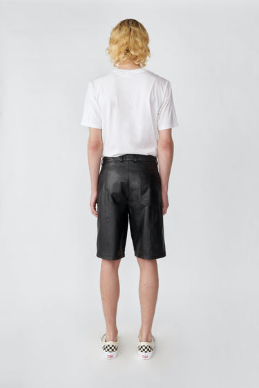 Model wearing Deadwood black knee-length board shorts. Hook and zipper closure and right back pocket. Made from recycled leather.