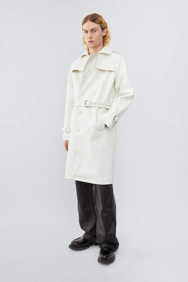 Model wearing white Deadwood military-inspired trench coat in vegan cactus leather. Classic details such as belt, flap yokes at shoulders and back, and slit at bottom hem.