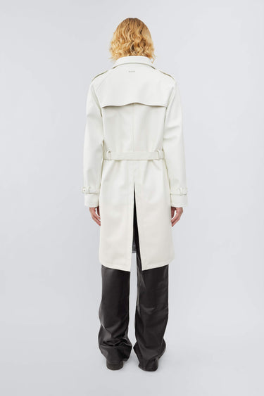 Model wearing white Deadwood military-inspired trench coat in vegan cactus leather. Classic details such as belt, flap yokes at shoulders and back, and slit at bottom hem.