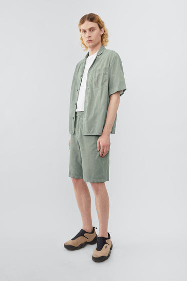 Model wearing Deadwood short sleeve suede shirt in the color ice, inspired by vintage hawaiian shirts. Made from recycled suede.