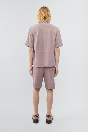 Model wearing Deadwood short sleeve suede shirt in the color lavender, inspired by vintage hawaiian shirts. Made from recycled suede.