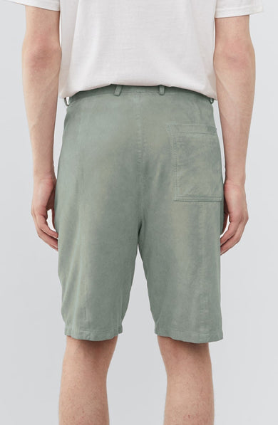 Model wearing Deadwood knee-length suede board shorts in the color ice. Hook and zipper closure and right back pocket. Made from recycled suede.