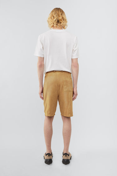 Model wearing Deadwood knee-length suede board shorts in the color mimosa. Hook and zipper closure and right back pocket. Made from recycled suede.